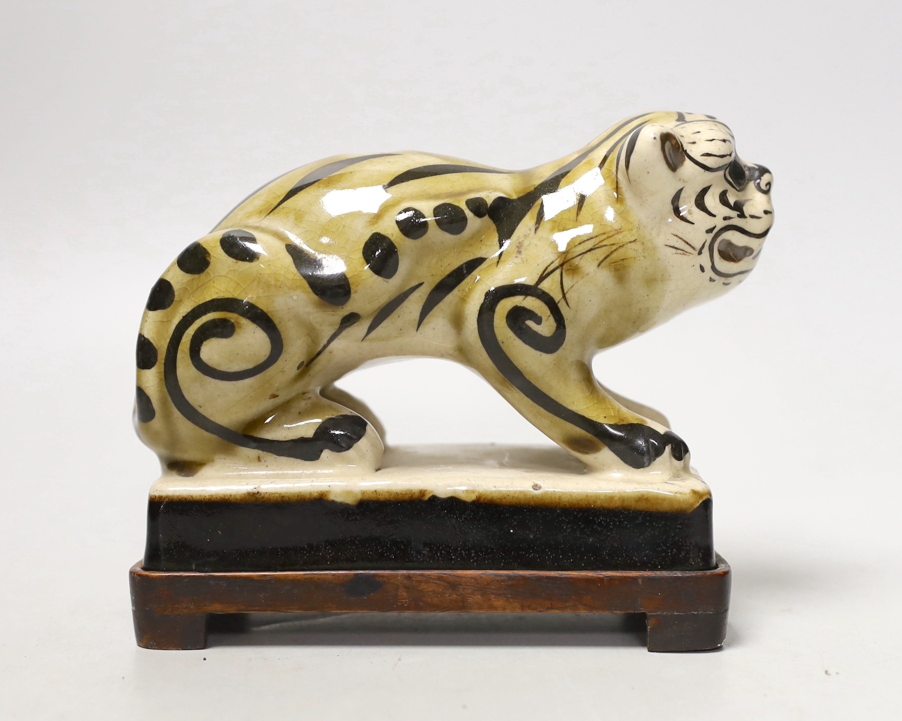 A Chinese Cizhou style pottery ‘tiger’ incense stick holder on wood stand, 13cm tall
